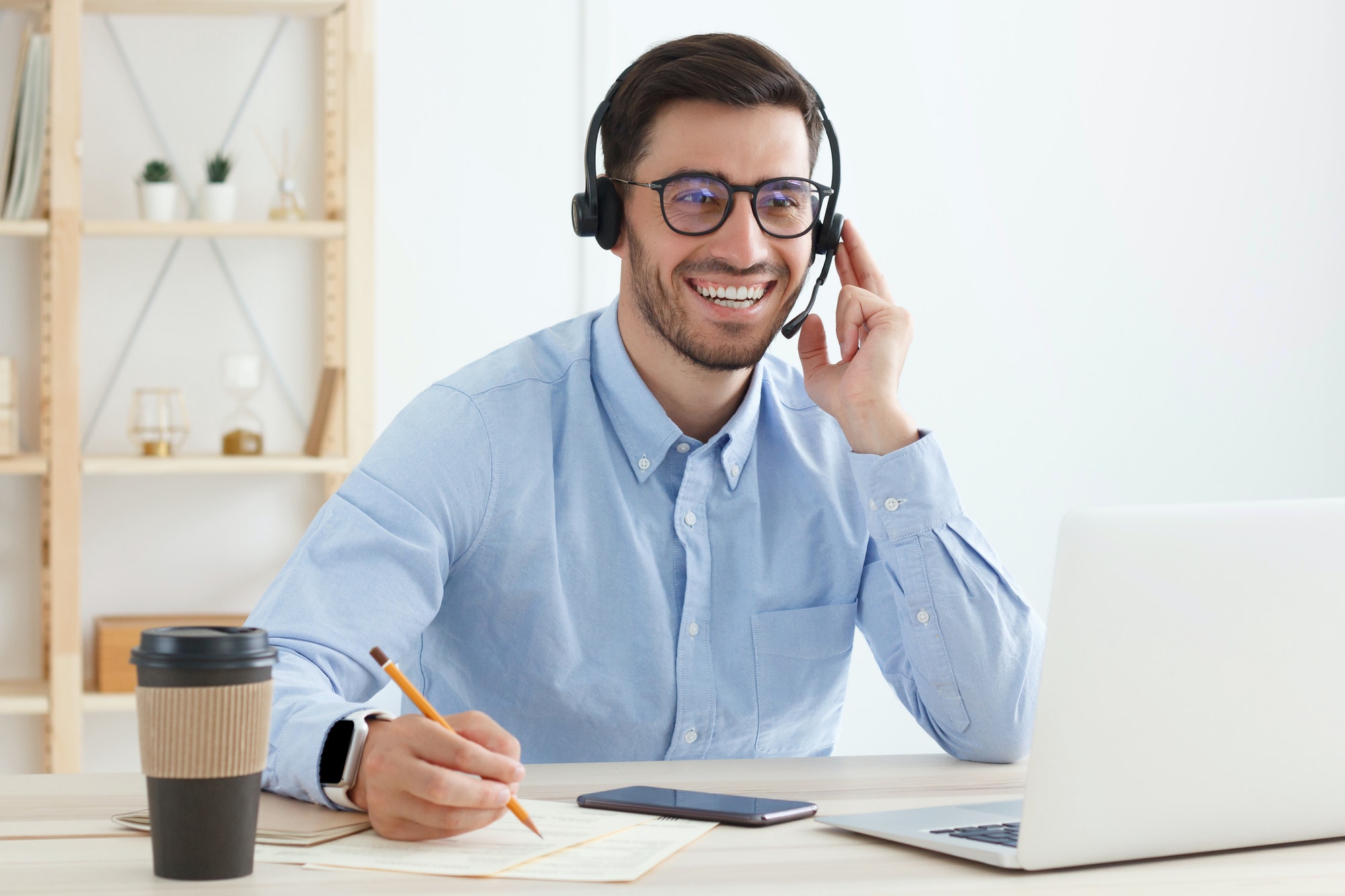 Smiling customer support service operator with hands-free headset working in office